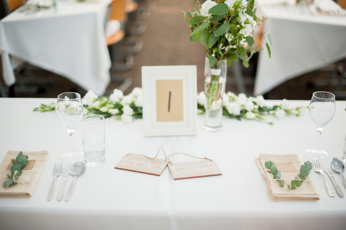 Kleine Holz-Schildchen und ein Fine-Art-Brautstrauß kennzeichnen den Brauttisch