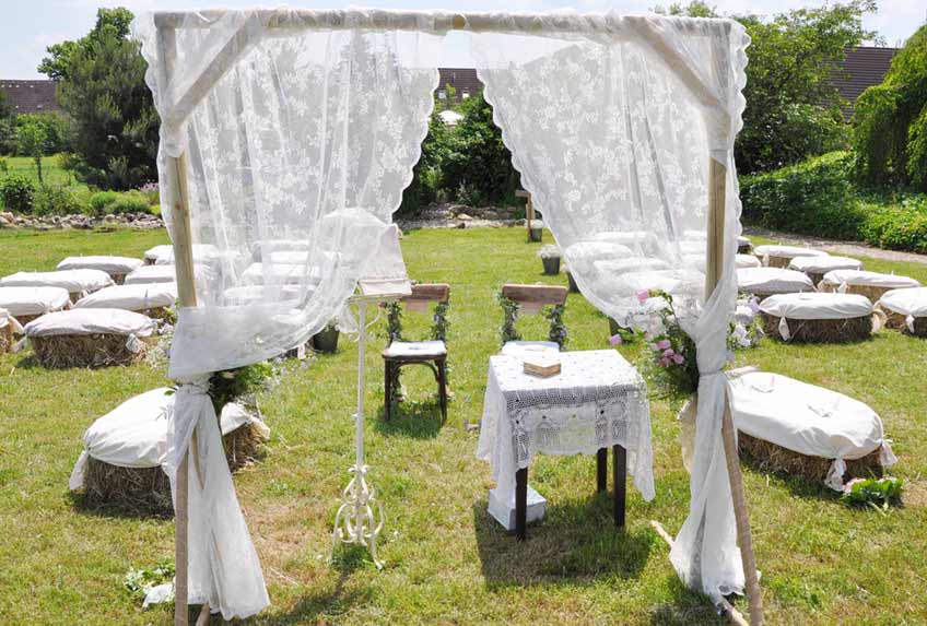 Ländliche Hochzeit unter freiem Himmel mit Heuballen, viel Holz und weißer Spitze (c) Nadine Bartholdt